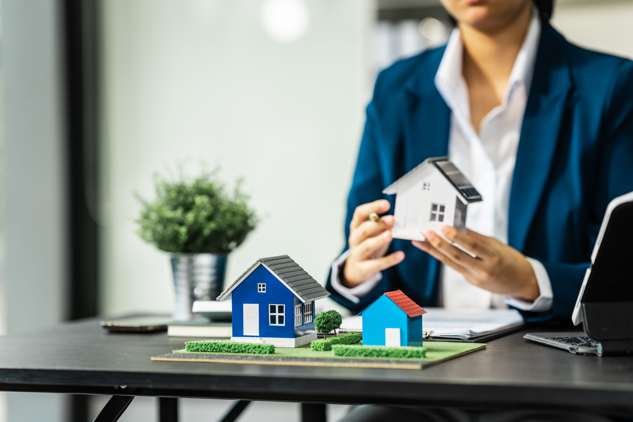 A businesswoman is reviewing contract papers at her desk in a sustainable house and condo